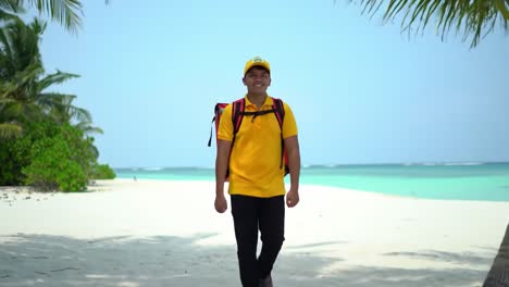 a young man dressed in a bright yellow shirt and hat strolls confidently on a beautiful sandy beach. lush palm trees frame the crystal-clear water, creating a tranquil atmosphere.