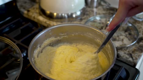 stirring a pan full of cheesy, creamy grits - shrimp and grits meal