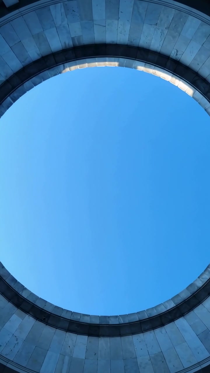 Vertical video: Tilting camera showing circular oculus at stone dome, revealing clear blue sky