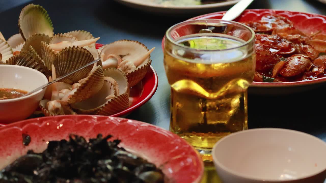 A vibrant display of seafood dishes and a glass of beer, capturing the essence of Thai cuisine in a lively setting