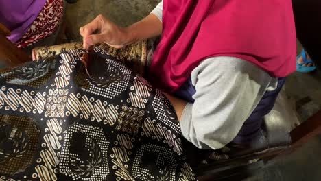 closeup video of indonesian old women making batik clothes