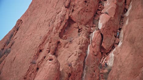 escaladores subiendo las rocas rojas del jardín de los dioses, bajo un cielo despejado