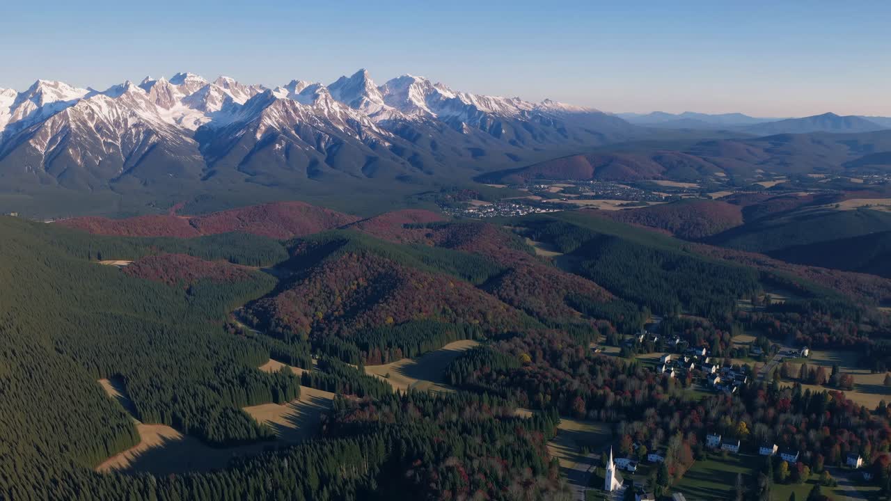 Aerial video capturing vast mountain ranges with snow-capped peaks and lush forests