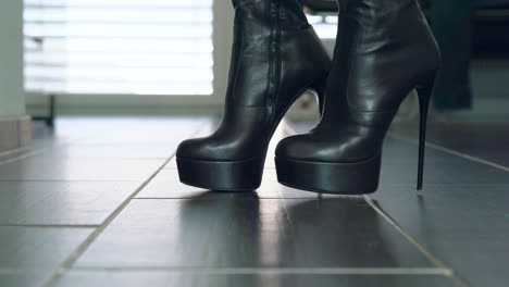 girl struts in front of the camera in black faux leather high heels block heel boots around