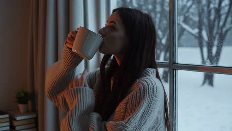 woman enjoying a hot drink by the window in winter