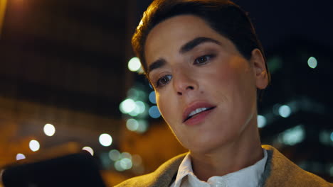 closeup woman looking smartphone at night city. beautiful businesswoman texting