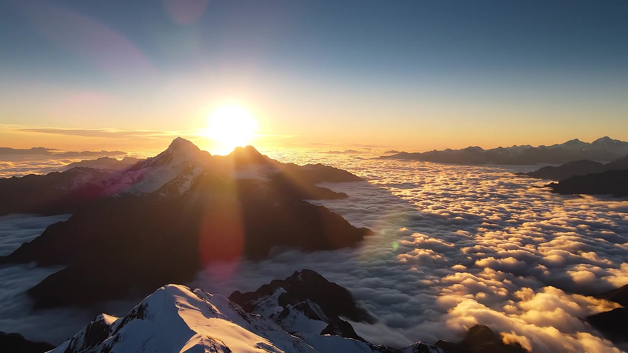 Majestic sunrise over snowy mountain peaks above sea of clouds