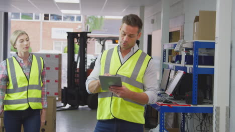 male and female workers in logistics distribution warehouse using digital tablet