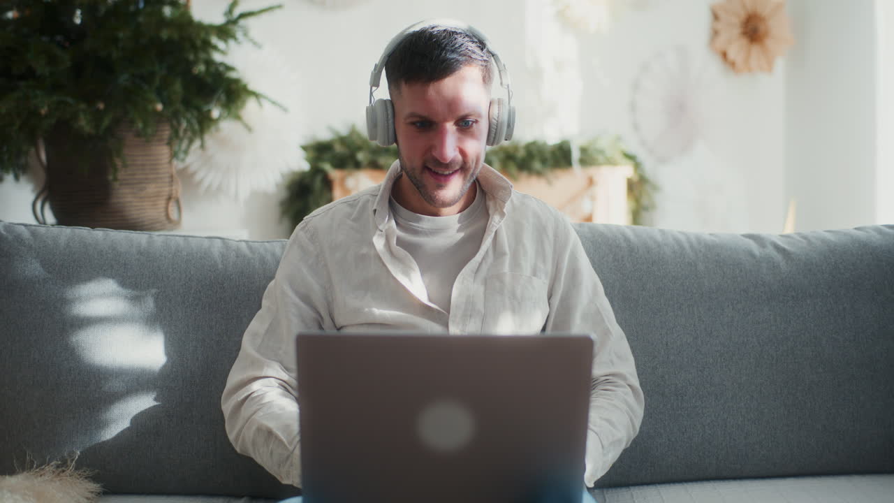 Homem Coloca os Fones de Ouvido Enquanto Trabalha no Laptop
