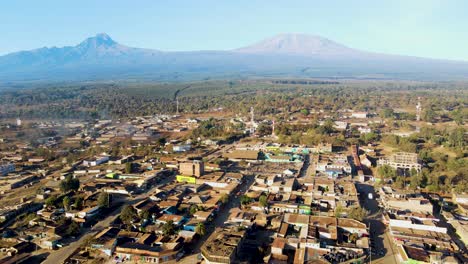 Amanecer:-Paisaje-De-Kenia-Con-Un-Pueblo,-Kilimanjaro-Y-El-Parque-Nacional-De-Amboseli---Seguimiento,-Vista-Aérea-De-Drones