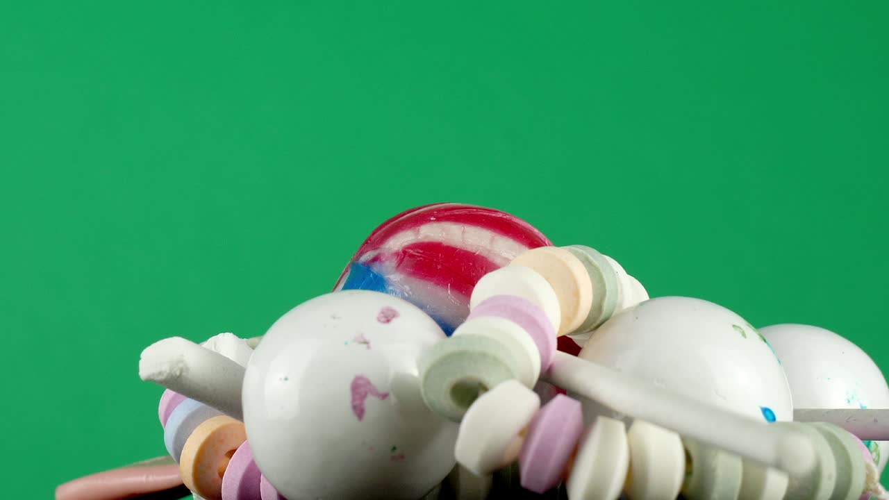 aislado frente a un fondo de estudio de pantalla verde, un puñado de golosinas azucaradas gira lentamente