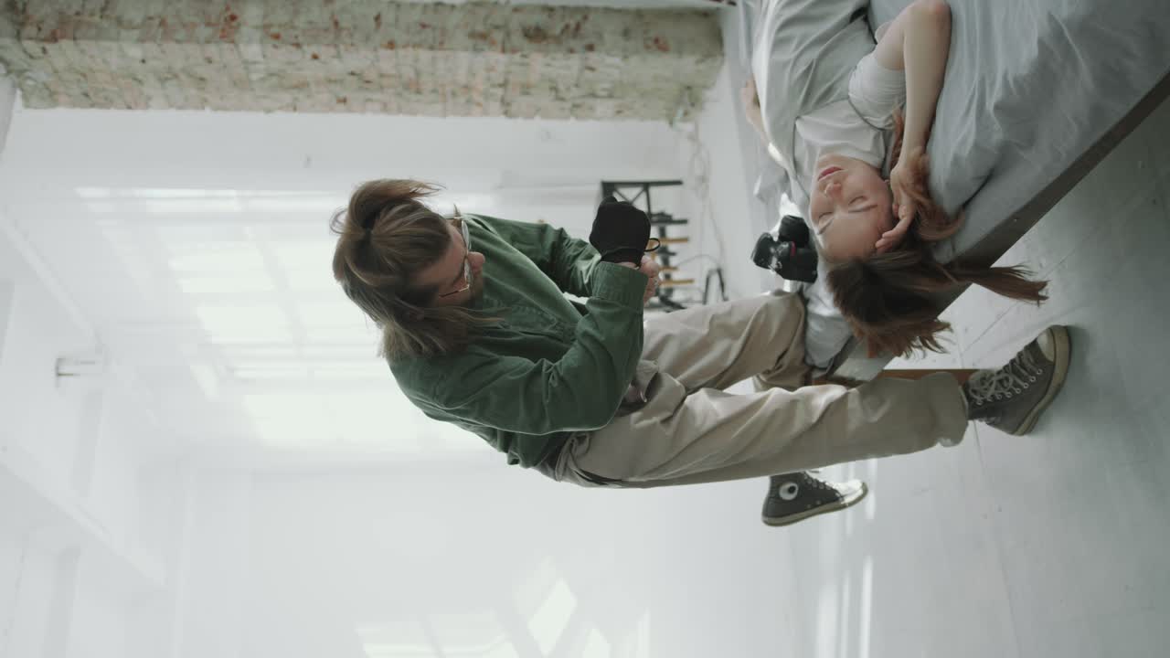 Photographer Taking Photos of Female Model Posing on Bed in Studio