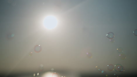 close-up of colorful bubbles floating gracefully in the air under a bright sun, creating a dreamy, ethereal scene with light rays piercing through the bubbles, enhancing the magical atmosphere