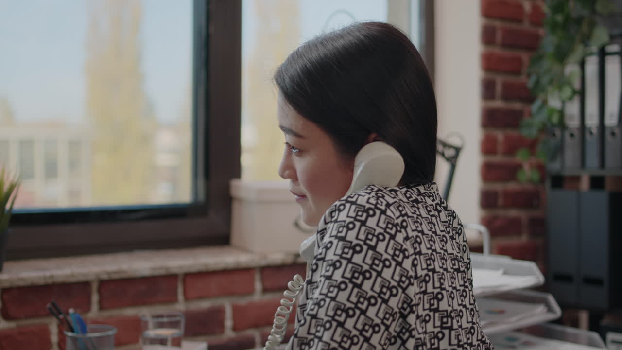 Business woman working and talking on landline phone