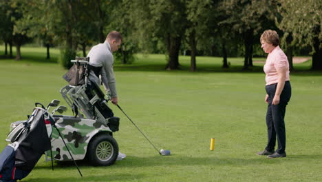 a golfer with a disability playing golf with a spotter