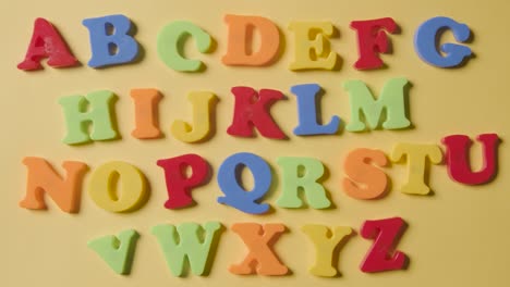 prise de vue aérienne en studio des lettres en plastique de l'alphabet disposées en ordre sur fond jaune