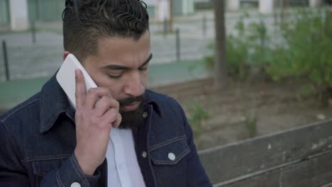hombre serio con portátil hablando por teléfono celular