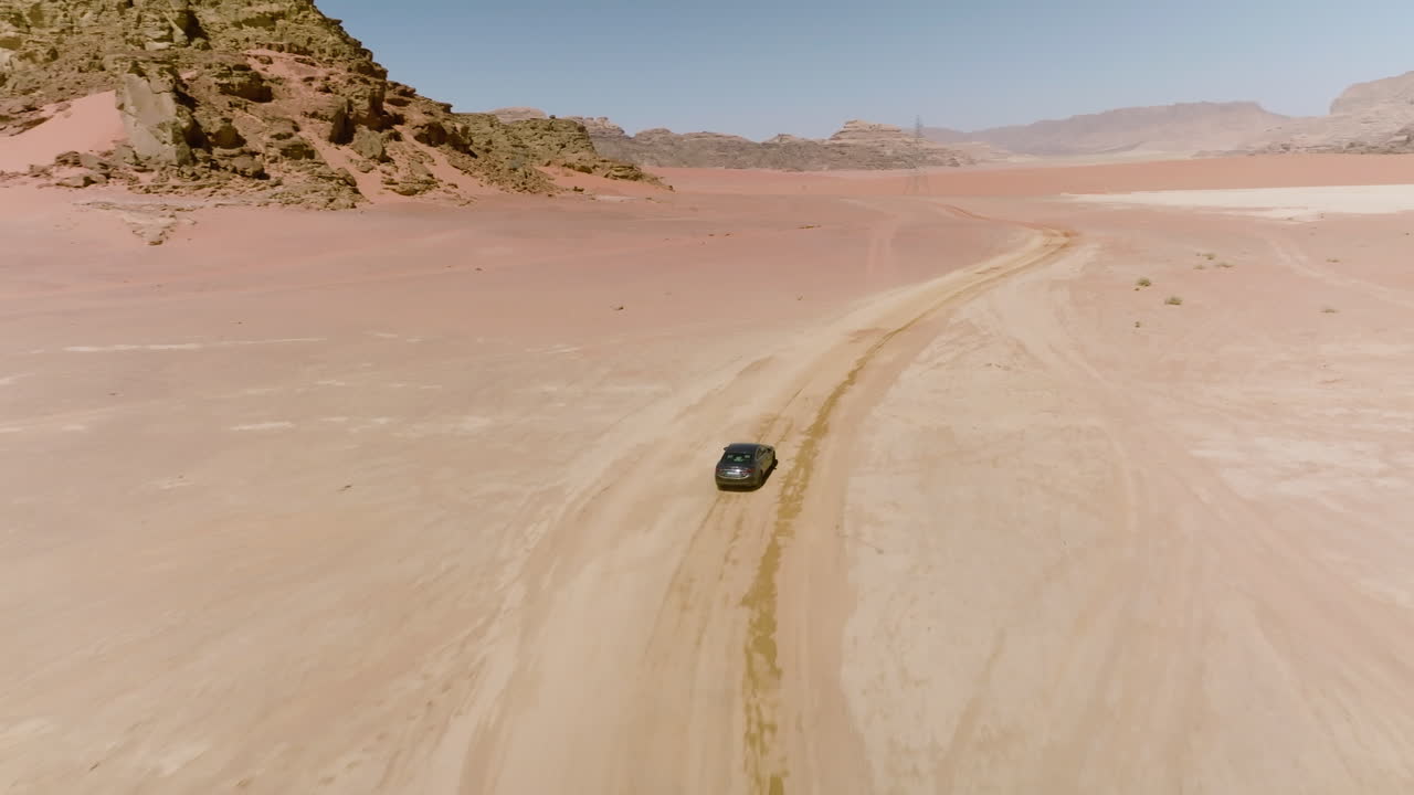 la antena sigue la conducción de un automóvil en un desierto de arena en wadi rum, jordania