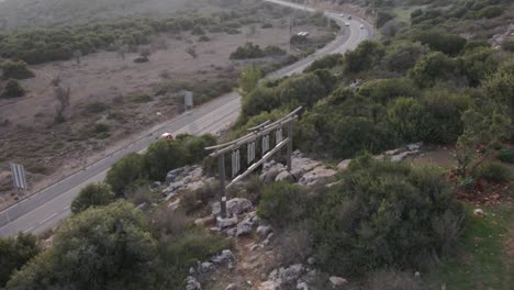 Toma-Aérea-De-Vehículos-Que-Se-Mueven-En-La-Carretera-En-Medio-Del-Bosque,-Drones-Volando-Sobre-árboles-Verdes-En-Un-Día-Soleado-En-Katzir-Israel