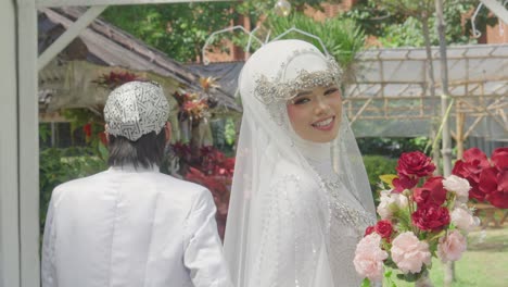 Vista-Trasera-De-Jóvenes-Recién-Casados-Asiáticos-Con-Vestido-Blanco-Tradicional-Y-Novia-Mirando-Hacia-Atrás-Sonriendo-A-La-Cámara