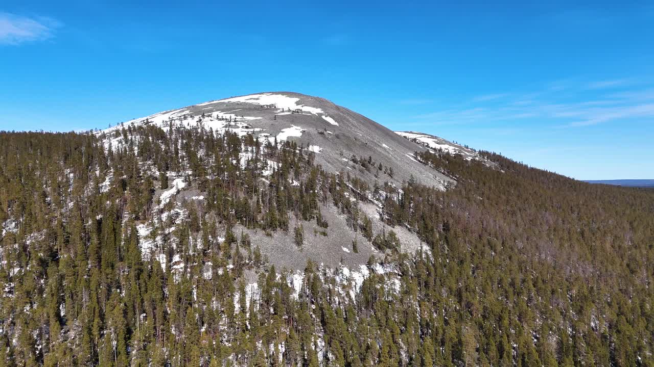 Aerial view closing in on a rocky mountain in Ylläs, Finland's Lapland region.