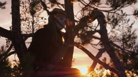 young girl with warm clothing sits in the nature against beautiful sunset flares