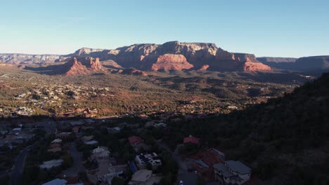 Drone-Shot-of-Sedona,-Arizona-USA-on-Sunny-Morning,-Homes-in-Valley-and-Red-Rock-Formations