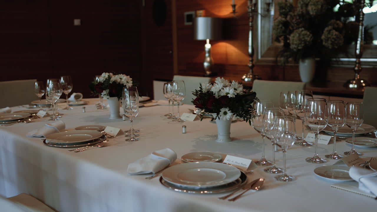 Elegant dining table with fine cutlery, wine glasses, and plush chairs in a formal setting, prepared for a high-level diplomatic dinner.