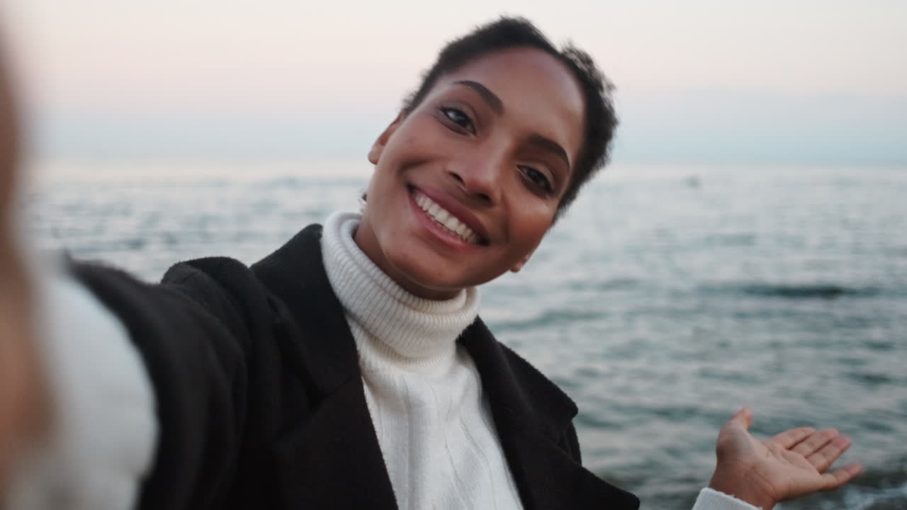 una chica afroamericana feliz agitando la mano hacia la cámara.