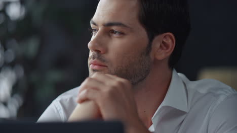 Thoughtful-businessman-sitting-at-remote-workplace-with-laptop-computer