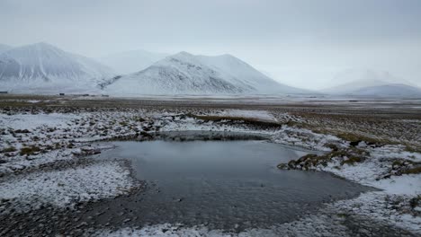 Lake-in-Iceland-Countryside-with-Majestic-Snow-Capped-Mountain-Backdrop,-Aerial