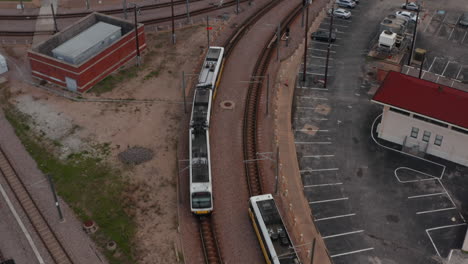 Aerial-view-of-two-electric-multiple-unit-trains-passing-by-each-other.-Metropolitan-passenger-DART-Light-Rail.-Drone-flying-forward-and-tilting-down.-Dallas,-Texas,-US