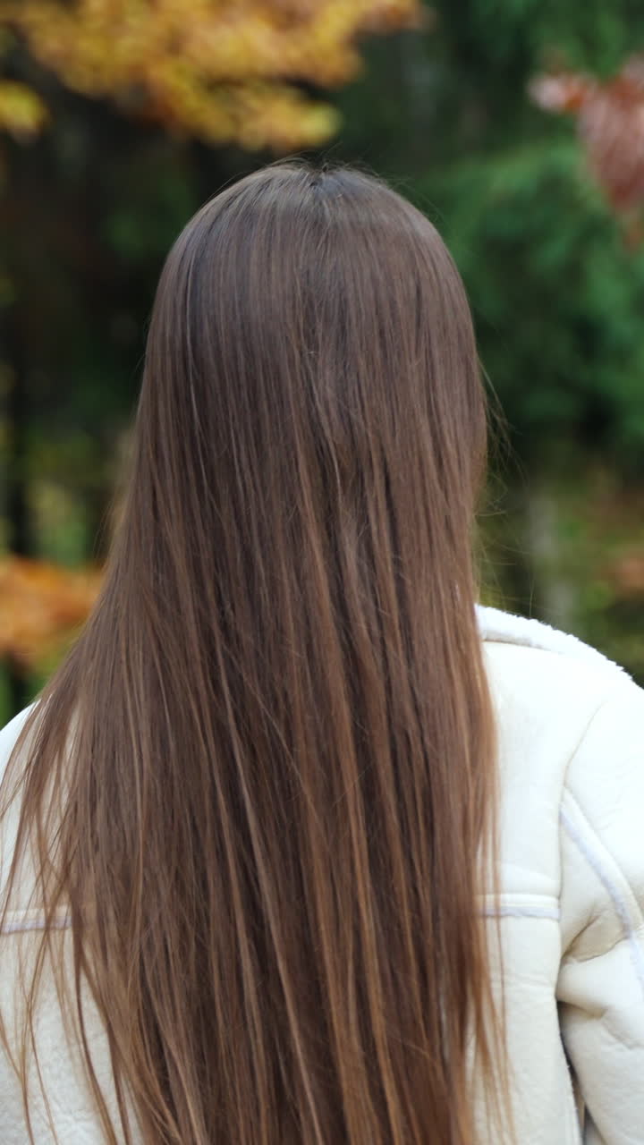 Portrait of cute lady walking in park. Young pretty woman walking in autumn forest. Vertical video