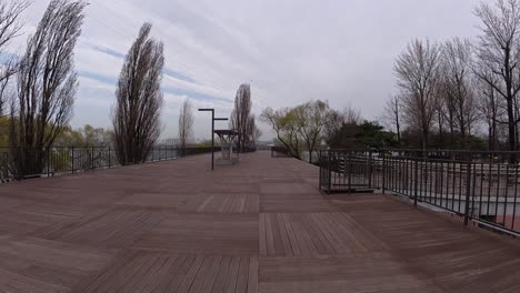 wooden boardwalk at seonyudo park on an overcast day with bench in seoul, south korea. - pov shot