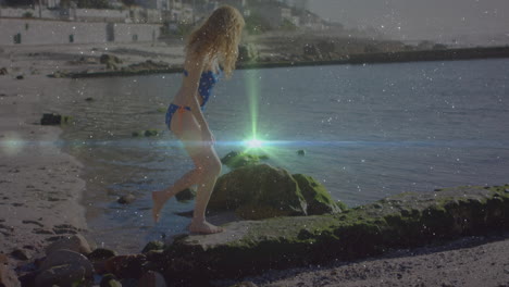 exploring rocky shoreline, woman in swimsuit with glowing light animation over water
