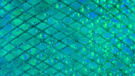 the flow of water directed to the metal mesh causes the bubbling of oxygen bubbles the flow of water directed to the metal mesh causes the bubbling of oxygen bubbles metal mesh in water covered with multicolored iridescent oxygen bubbles due to a blue green blurred background slow motion close up
