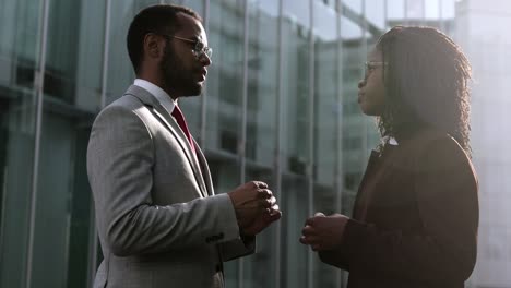 Side-view-of-two-self-assured-workers-talking-outdoor.