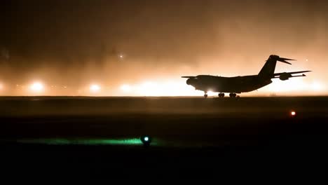 avión de carga militar aterrizando por la noche en la niebla