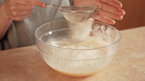 sifting flour into a mixing bowl for baking