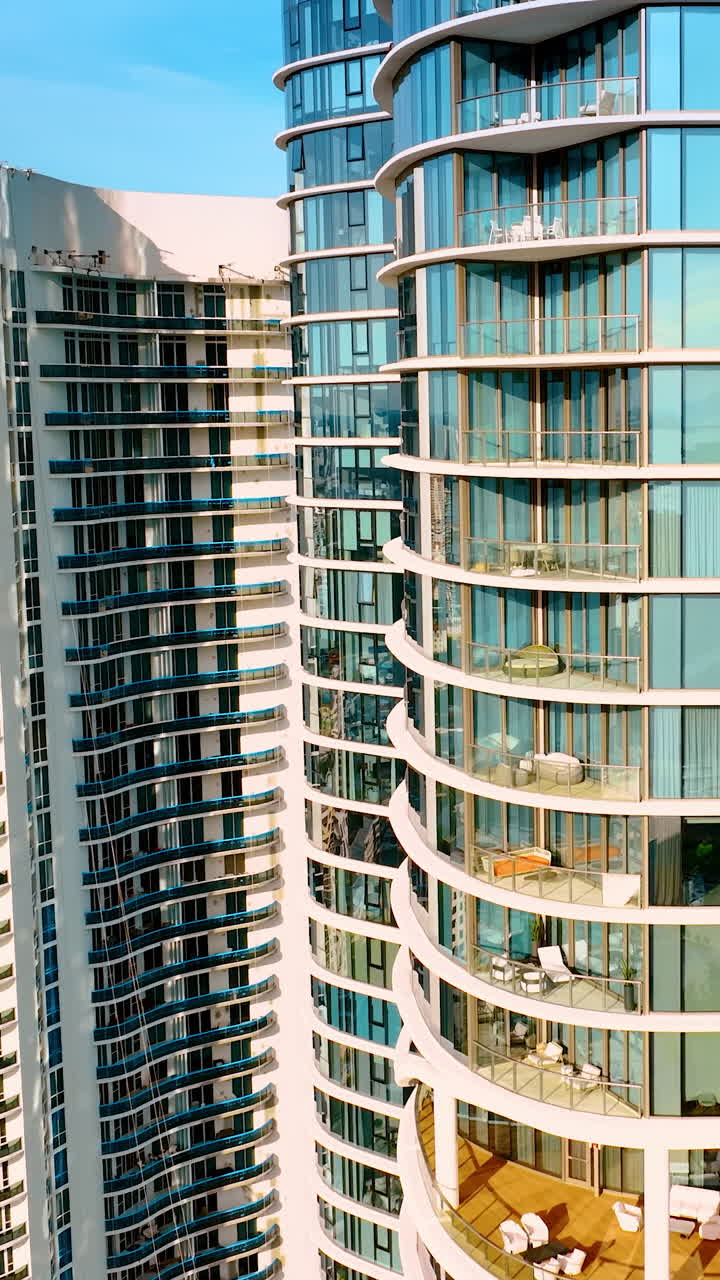 Drone approaching the beautiful high-rise apartment block on the coast of the Atlantic Ocean. Miami Beach architecture on sunny day. Vertical video