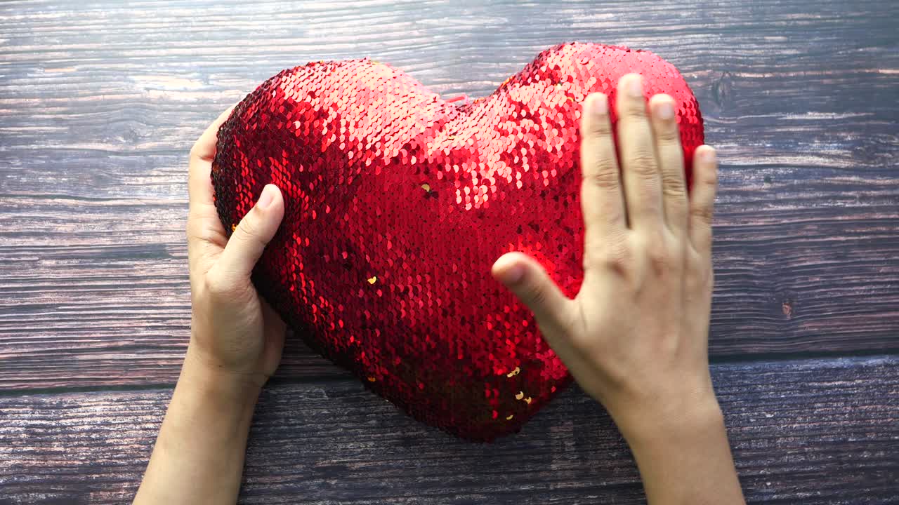 руки, держащие красную подушку для сердца