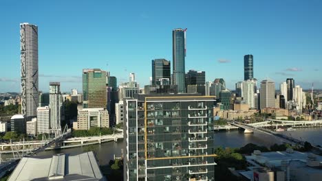 stunning aerial drone shot, rotating around a large apartment building in the heart of west end, with the city, river and south bank visible in the background