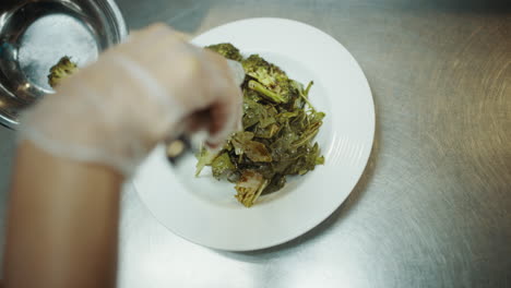 chef colocando brócoli en un plato de ensalada