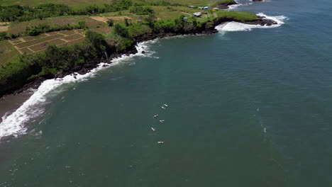 Un-Grupo-De-Surfistas-Esperan-Olas-En-La-Playa-De-Bali,-Cerca-De-Tanah-Lot,-Indonesia