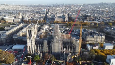 drone moving forward approaching notre dame church in paris during renovation, many cranes