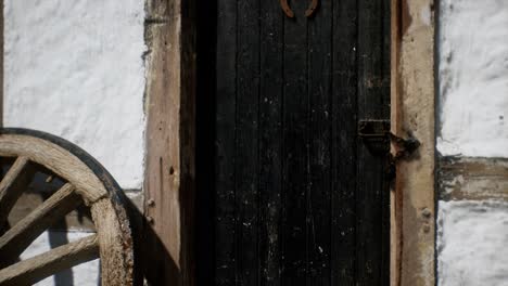 old wood wheel and black door at white house