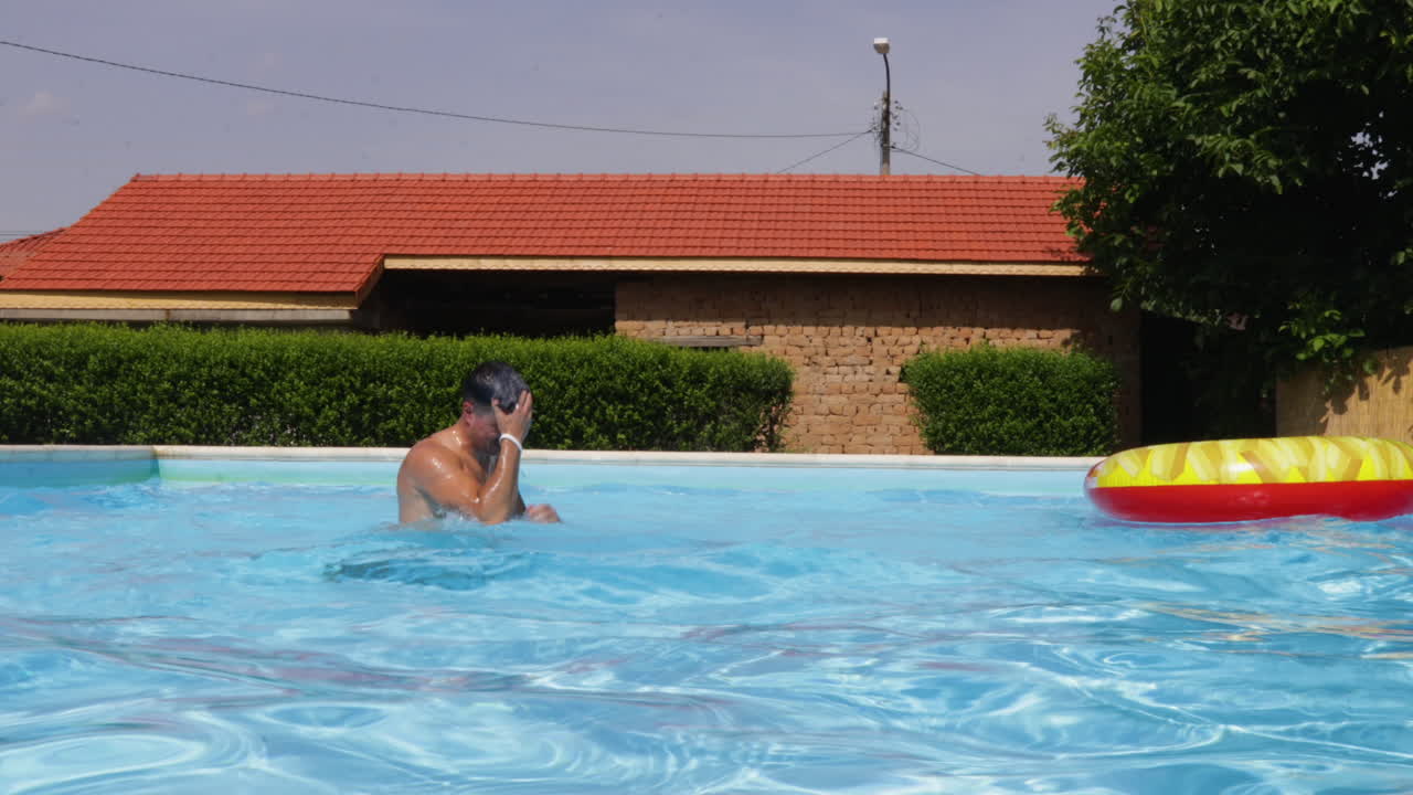 hombre tratando de mantener el equilibrio y cae de la cama de la piscina inflable, vista estática