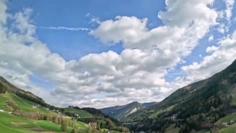 cloudy blue sky over austrian mountain valley with forest and green farmland