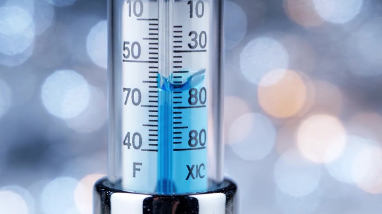 Detailní pohled na teploměr měřící teplotu v krásně osvětleném prostředí, ukazující účinky sezónních změn na atmosférické podmínky.