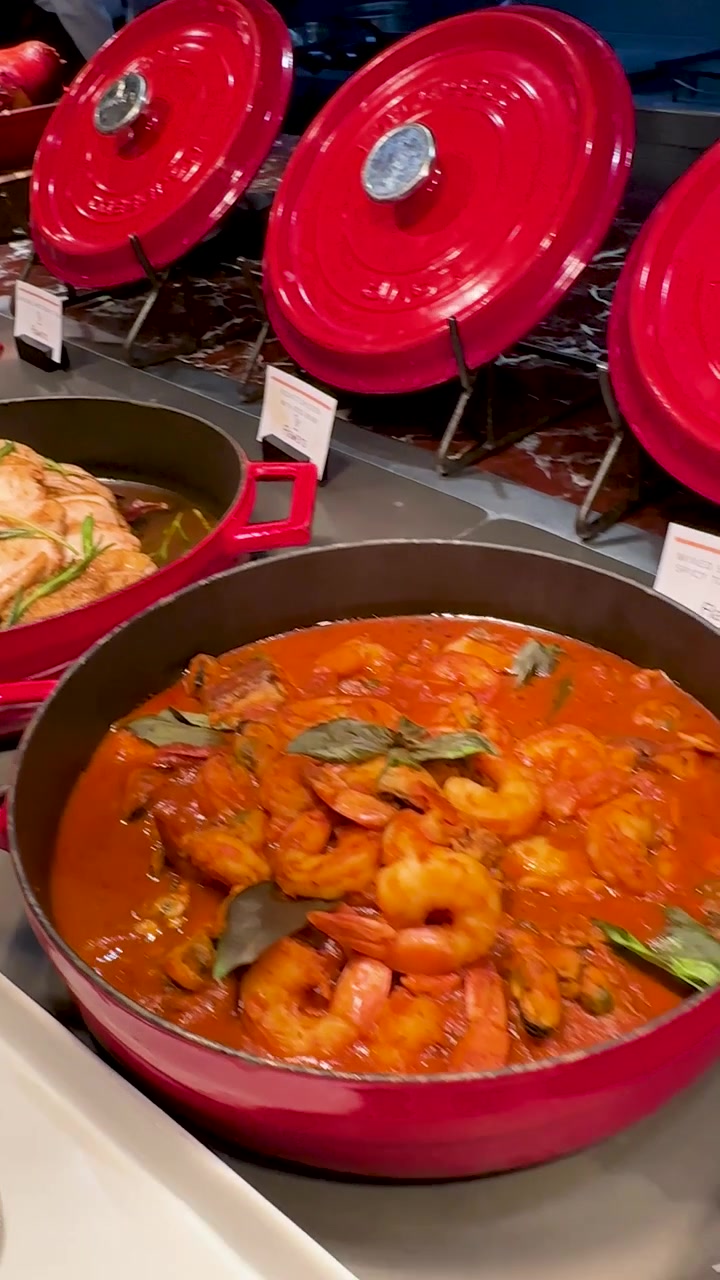 Una telecamera riprende un buffet di lusso con vari piatti gourmet in pentole rosse